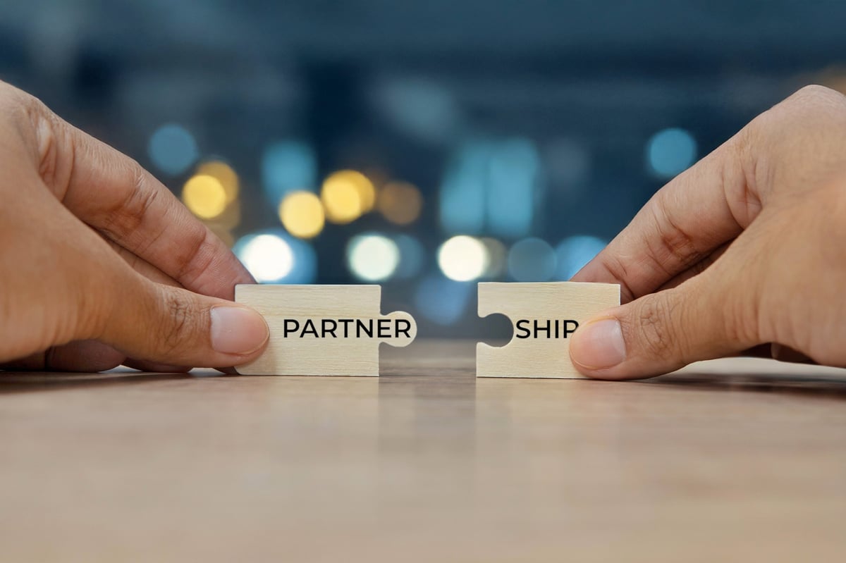 Hands assembling puzzle pieces together in partnership